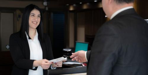 a woman in a suit holding a remote control at Abc Hotel in Thessaloniki