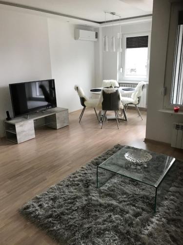 un soggiorno con televisione, tavolo e sedie di Apartman Oslo a Belgrado