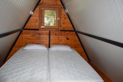 a bed in a tiny house with a window at Camping Kea in Pisses