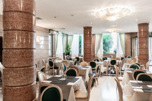 a restaurant with tables and chairs and a chandelier at Hotel Catullo in San Martino Buon Albergo