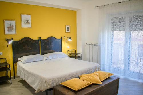 1 dormitorio con 1 cama grande y pared amarilla en B&B Fleurs, en Enna