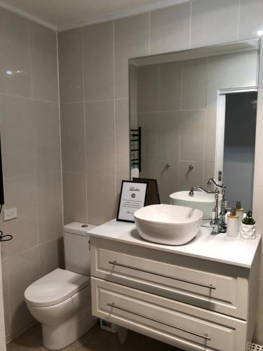 a bathroom with a sink and a toilet and a mirror at Sunny Corner Lake Eildon in Eildon