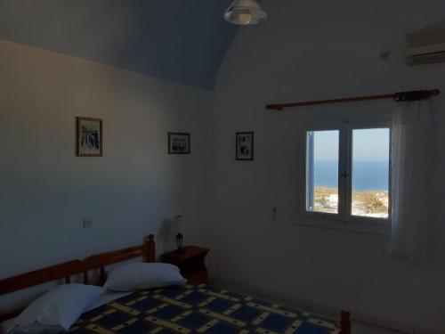 um quarto com uma cama e uma janela em Katerina Kafieri Apartments em Firostefani