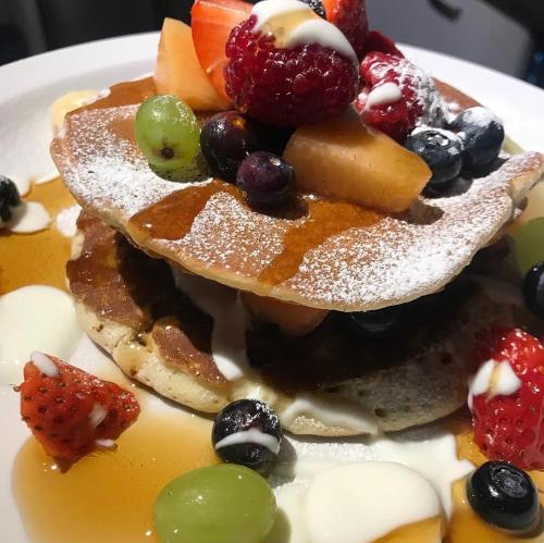 a stack of pancakes with fruit on a plate at Ardlogie Guest House in Aviemore