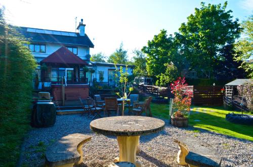 a garden with a table and chairs and a house at Ardlogie Guest House in Aviemore