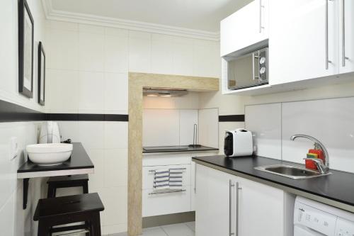 - une cuisine blanche avec des placards blancs et un évier dans l'établissement Casa Ginja - Checkinhome, à Lisbonne