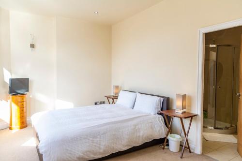 a white bedroom with a bed and a tv at Apartment No 1 - The Old Red King Pub, Whitefield, Manchester in Manchester