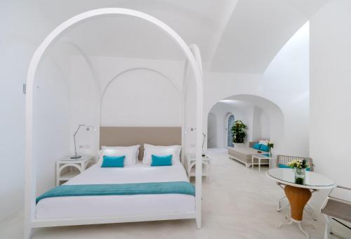 a white bedroom with a bed and a table at Bellevue Syrene in Sorrento