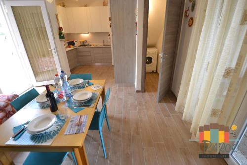 a dining room table with plates on it and a kitchen at Fiordo Corallo in Isola Albarella