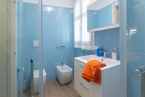 La salle de bains bleue est pourvue d'un lavabo et d'une douche. dans l'établissement Villa Sofia, à Rosolina Mare