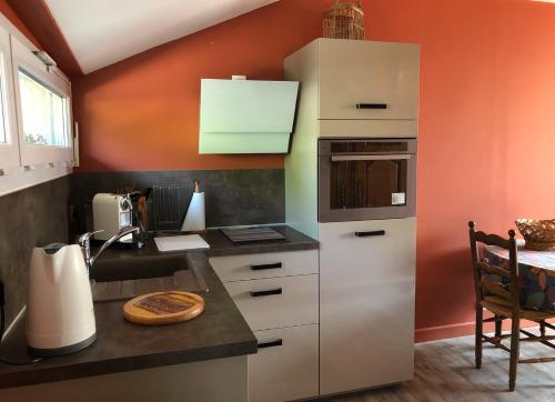 a kitchen with white cabinets and an orange wall at Le Clos des Moulins in Hautvillers