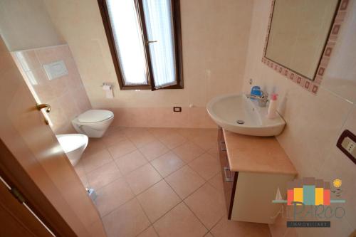 La salle de bains est pourvue de toilettes, d'un lavabo et d'un miroir. dans l'établissement Villa Aurora, à Albarella