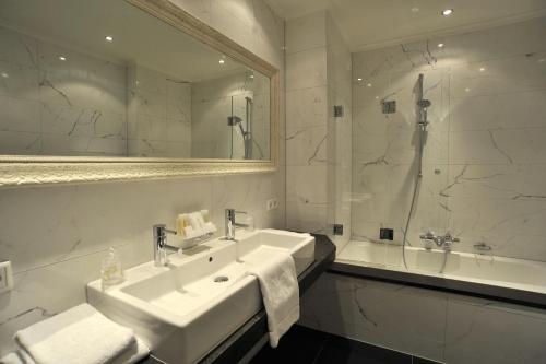 a bathroom with a sink and a tub and a mirror at Villa Rubenshof in Helmond