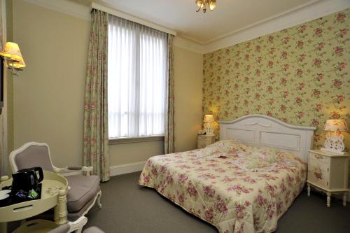 a bedroom with a bed and a chair and a window at Villa Rubenshof in Helmond