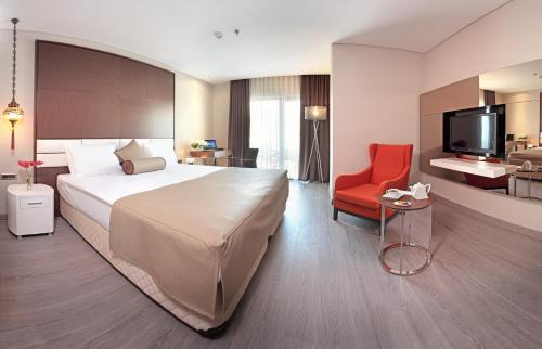 イスタンブールにあるイスタンブール ドラ ホテルの大きなベッドと赤い椅子が備わるホテルルームです。