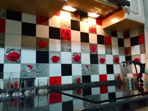 una encimera de cocina con rosas rojas en una pared a cuadros en Димитрова 80/1 Апартаменты в Темиртау, en Temirtaū