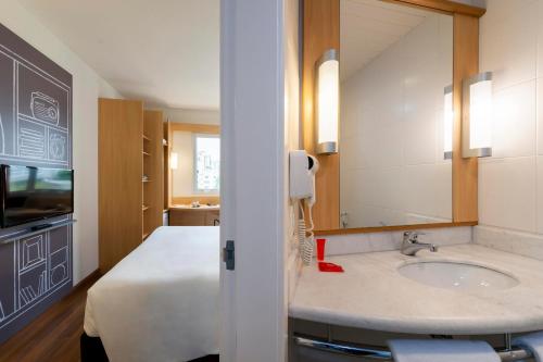 a hotel bathroom with a sink and a bed at ibis Sao Jose in São José