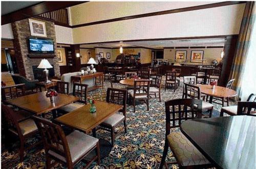 a restaurant with wooden tables and chairs and a room filled with tables at Staybridge Suites Williamsville Buffalo by IHG in Williamsville