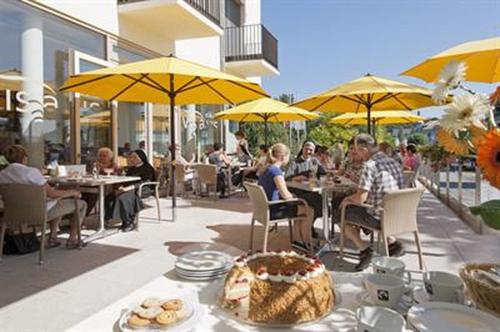 a group of people sitting at tables with yellow umbrellas at Hotel St Elisabeth in Allensbach
