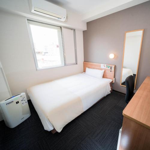 a bedroom with a large white bed and a window at Super Hotel Yamaguchi Yuda Onsen in Yamaguchi