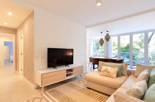 a living room with a couch and a flat screen tv at Tropical View Cascais - CheckinHome in Cascais