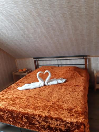 two towels in the shape of a heart on a bed at Sodyba Vieversynė in Duokiškis