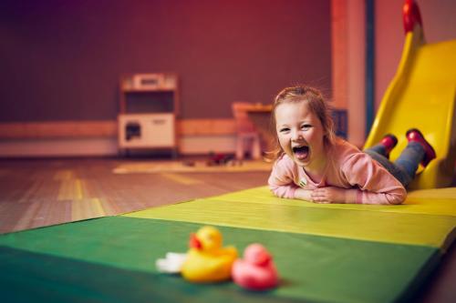 a little girl laying on the floor with rubber ducks at WestCord ApartHotel Boschrijck in West-Terschelling