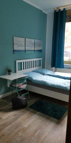 1 dormitorio con cama, mesa y pared azul en Pension Kaffeefreunde en Berlín