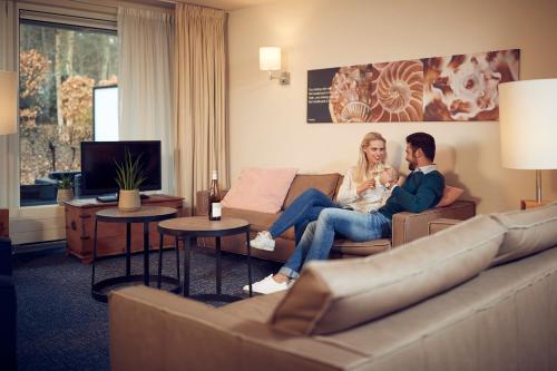 a man and woman sitting on a couch in a living room at WestCord ApartHotel Boschrijck in West-Terschelling