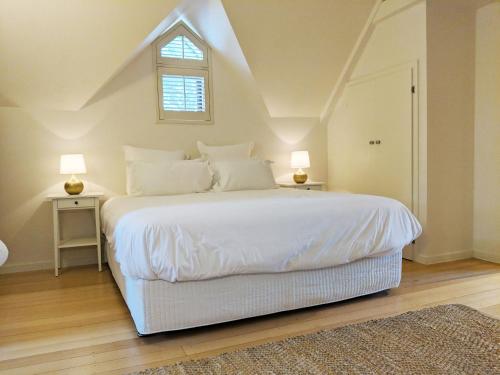 ein Schlafzimmer mit einem großen weißen Bett mit zwei Lampen in der Unterkunft El Camino country cottage with terrace and stunning views in Hepburn Springs