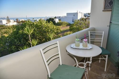 a balcony with a table with two drinks on it at Porto Manolis in Agios Ioannis Tinos