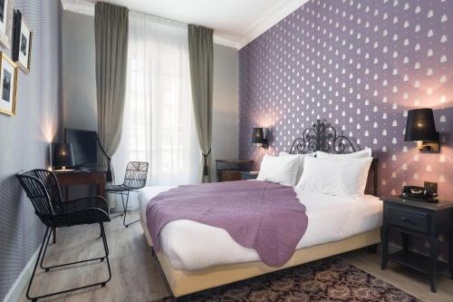 a bedroom with a large bed with a purple blanket at Hotel Le Grimaldi by Happyculture in Nice