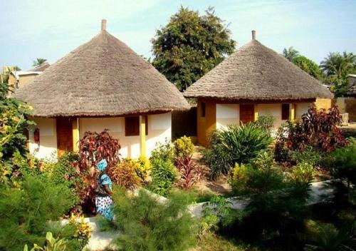 zwei Hütten mit Strohdächern in einem Garten in der Unterkunft Le Petit Quartier "Chez Amanthia" in Cap Skirring