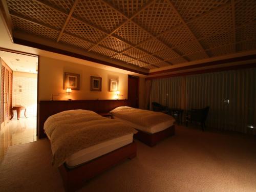 a bedroom with two beds and a coffered ceiling at Nishiizu Crystal View Hotel in Nishiizu