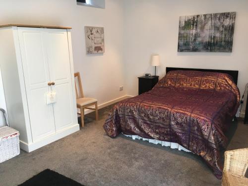 - une chambre avec un lit, une armoire et une chaise dans l'établissement Bagstone Court Barn, à Rangeworthy