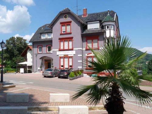 a large house with a palm tree in front of it at Hotel Markgräfler Hof in Badenweiler