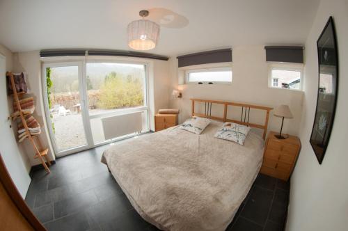 a bedroom with a bed and a large window at Gîte Perle d'Ô in Profondeville