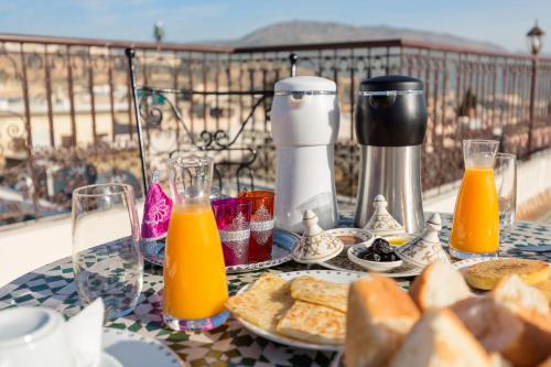 a table with food and orange juice and bread at Le Grand Alcazar - Riad in Fès