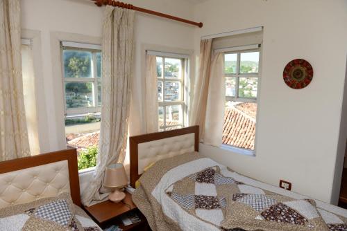 a bedroom with two beds and two windows at Guest House Taunus in Berat