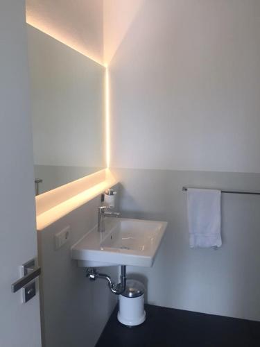 a bathroom with a white sink and a light at Studio mit Alpenblick in Kleinweil