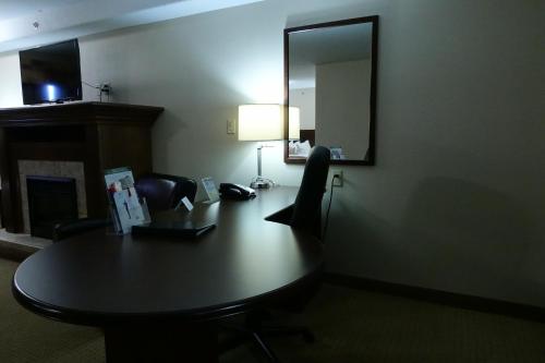 a desk in a hotel room with a table and a mirror at Ramada by Wyndham Weyburn in Weyburn
