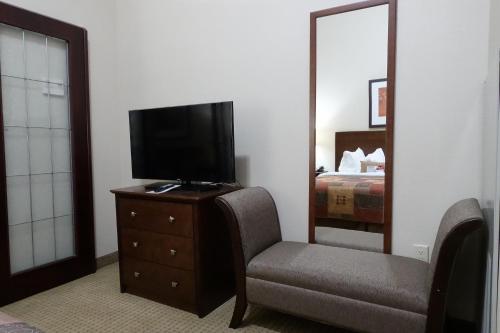 a bedroom with a tv and a chair and a bed at Ramada by Wyndham Weyburn in Weyburn