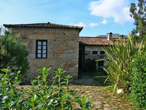 an old stone building with a window in a yard at Moinho de Estoraos in Ponte de Lima