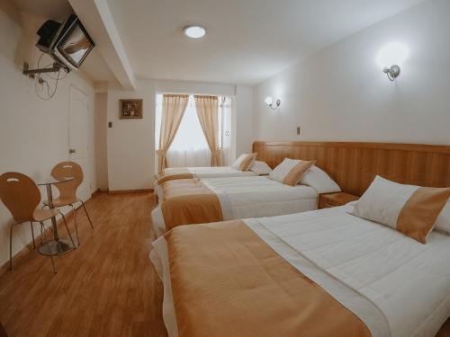 a hotel room with three beds and a table at Hotel MST Colonial in Iquique