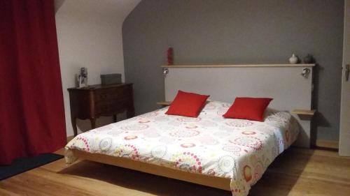 a bedroom with a bed with two red pillows at La Source in Saint-Amand-Magnazeix