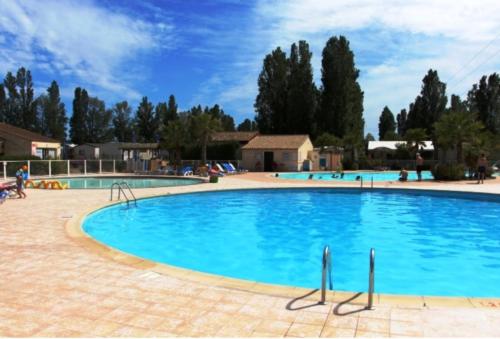 une grande piscine bleue avec des arbres en arrière-plan dans l'établissement Mobile Home Neuf AZ 27, à Fréjus