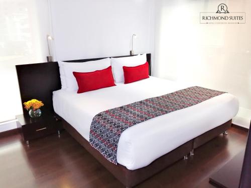 a bedroom with a large bed with red pillows at Richmond Suites Hotel in Bogotá
