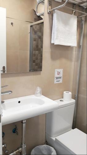 a bathroom with a sink and a toilet and a mirror at Puerta Alameda Suites Mirador Centro Historico in Ronda
