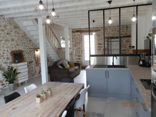 cocina y sala de estar con mesa de madera en GITE IZALIN AVEC SPA A 20 min du Puy du Fou en Mauléon
