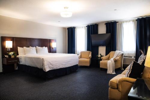 a hotel room with a bed and two chairs at Hatfield Inn in Leitchfield